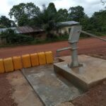 Pompe à main d'un forage d'eau potable au bord d'un chemin de latérite dans le Niari