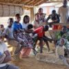 Habitants du village de Kola réunis sous un abri en bois et bambou lors d'une séance de sensibilisation
