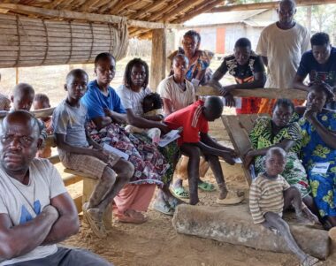 Habitants du village de Kola réunis sous un abri en bois et bambou lors d'une séance de sensibilisation